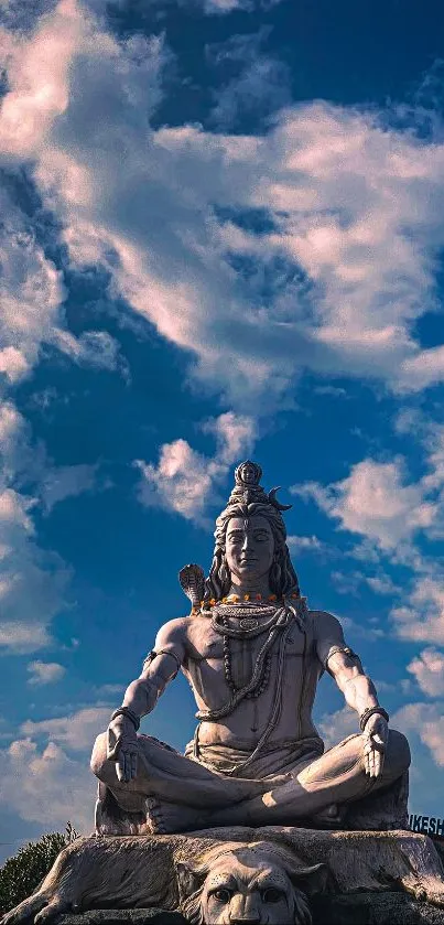 Serene Shiva statue under vibrant blue sky with clouds and greenery.