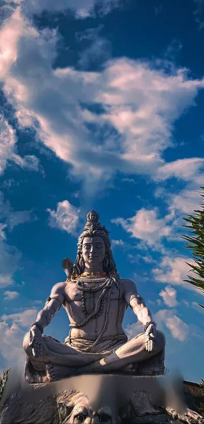 Shiva statue against a vibrant blue cloudy sky, exuding peace and serenity.