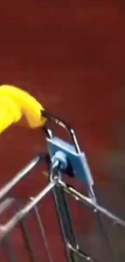 Shopping cart with yellow handle against a blurred red background.