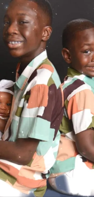 Smiling siblings in colorful shirts with a baby on a dark background.