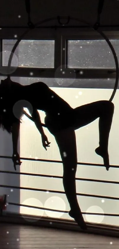 Silhouette of an aerial hoop artist posing gracefully.