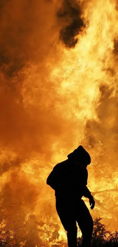 Silhouette standing in front of intense orange flames.