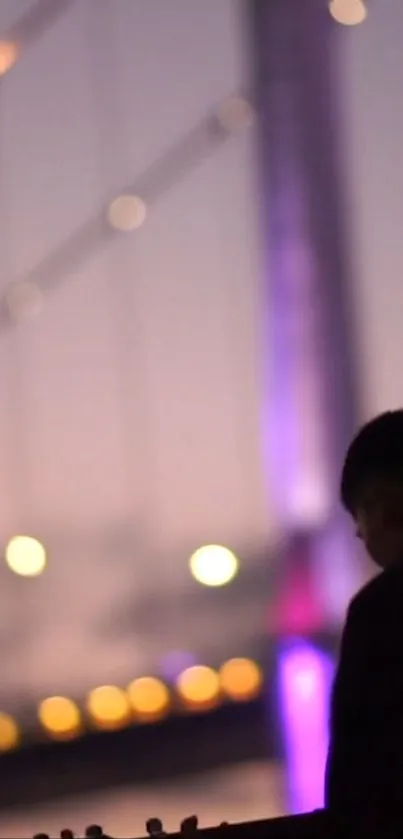 Silhouette of person with glowing bridge at dusk.