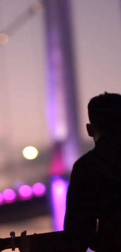 Silhouette of guitarist with purple lit bridge at dusk.