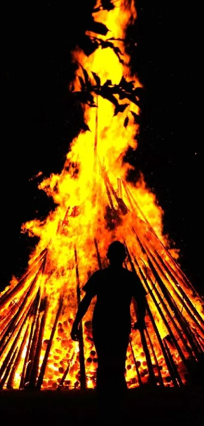 Silhouette in front of a glowing bonfire at night.