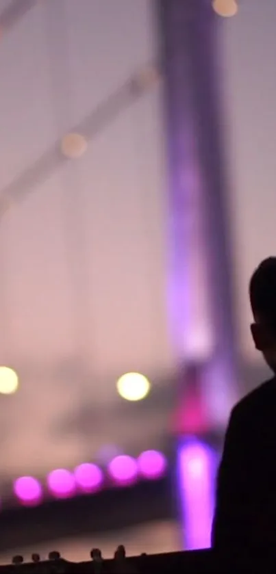 Silhouette of a person against a lit bridge at night.