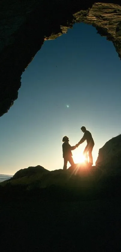 Silhouette of two people in a cave at sunset.