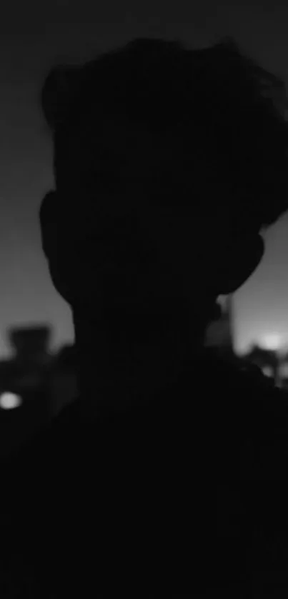 Silhouette of person against a cityscape at night.