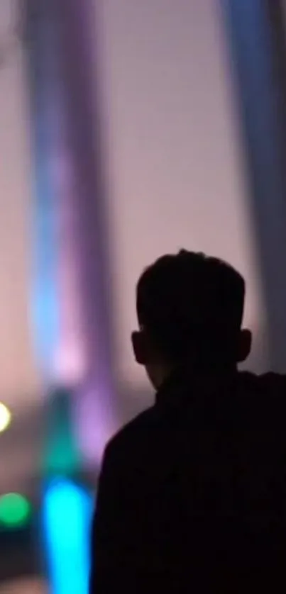 Silhouette of a person with colorful urban evening lights in the background.