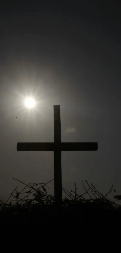 Silhouette of a cross against a bright sun in a dark sky.