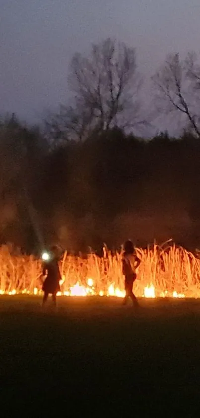 Two silhouettes near a burning field at night.