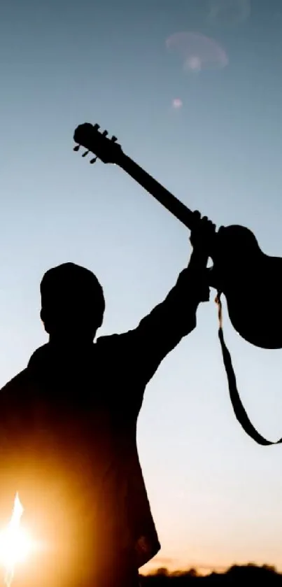 Silhouette holds guitar against sunset sky.