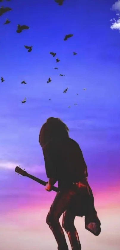 Silhouette of guitarist at sunset with birds in the sky.