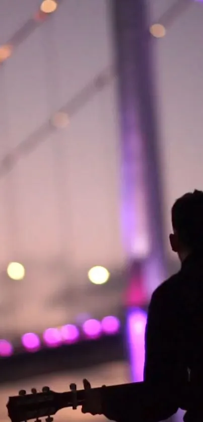 Silhouette of a guitarist at twilight with a purple light bridge in background.