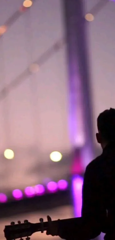 Silhouette of a guitarist with a glowing purple-lit bridge at night.