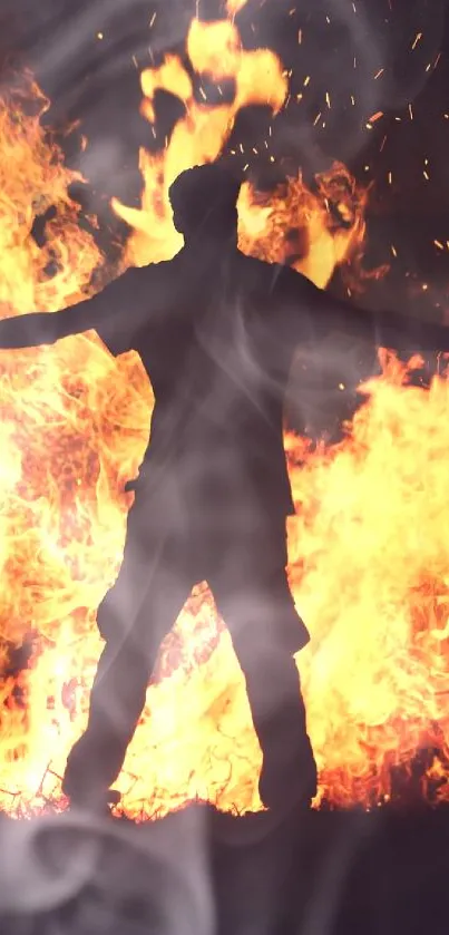 Silhouette of a person standing in front of a large fire at night.