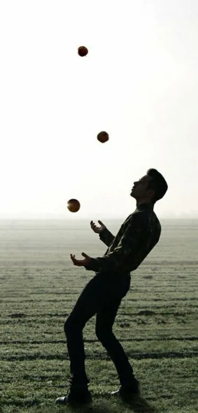 Silhouette of a person juggling balls in a misty morning field.