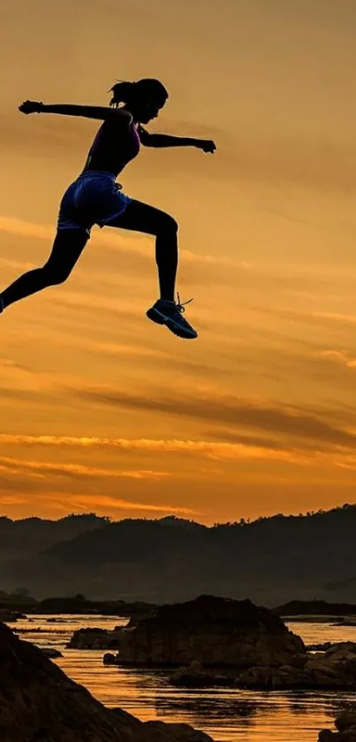 Silhouette of person jumping at sunset over a mountain landscape.