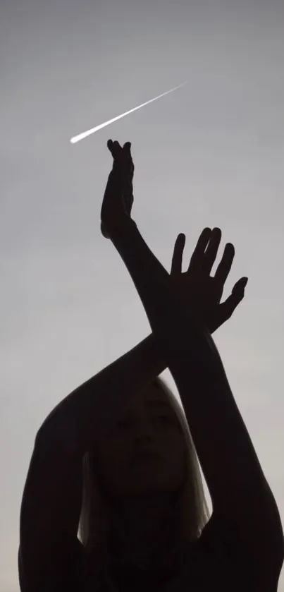 Silhouette of person with meteor in a gray sky.