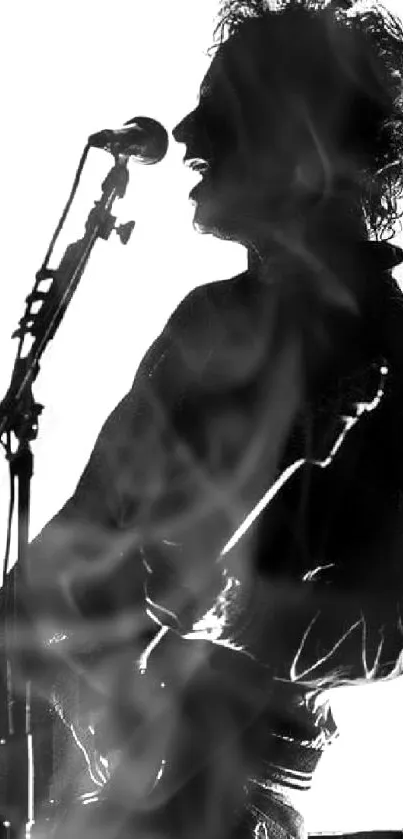 Silhouette of a musician playing guitar on stage in black and white.