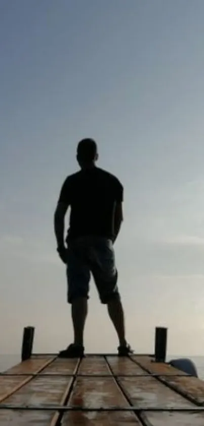 Silhouette on a wooden pier with a serene sky.