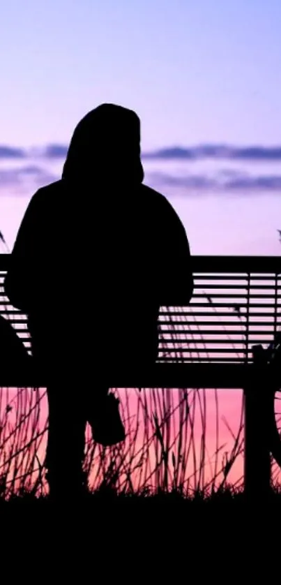 Silhouette sitting on a bench against a pink and purple sunset sky.