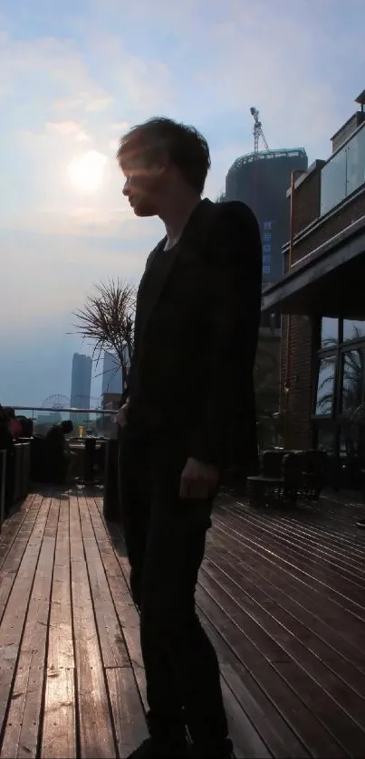 Silhouette on a rooftop deck during sunset with a city view.