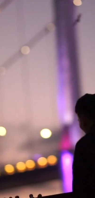 Silhouette against a vibrant, lit bridge at dusk.