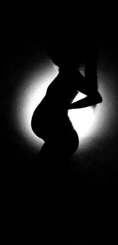 Silhouette of a pregnant woman against light background.