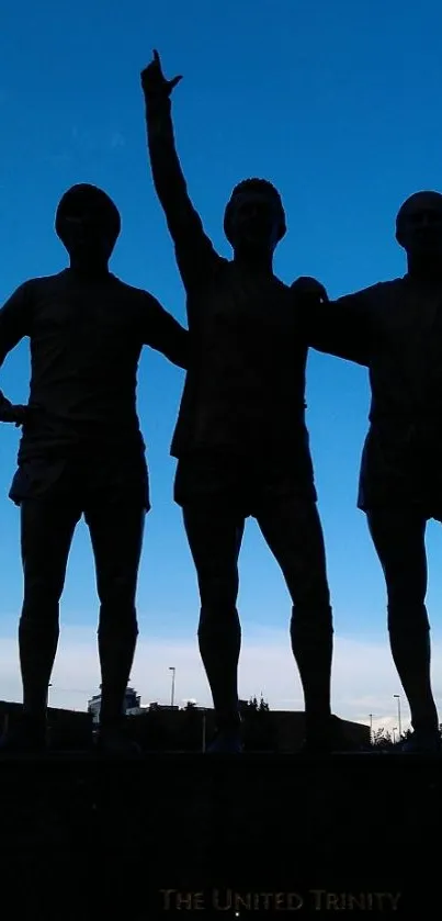 Silhouette of three statues against a vibrant blue sky.