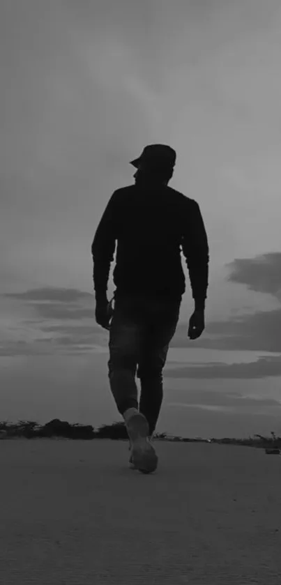 Silhouette of a person walking during a gray sunset evening on a deserted path.