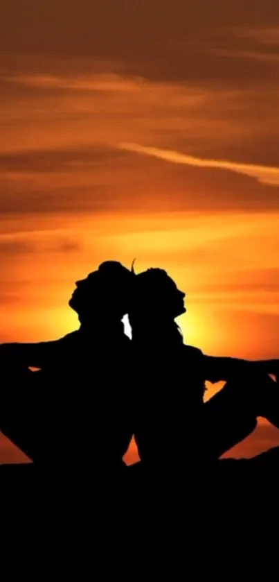 Silhouette of a couple against an orange sunset sky.