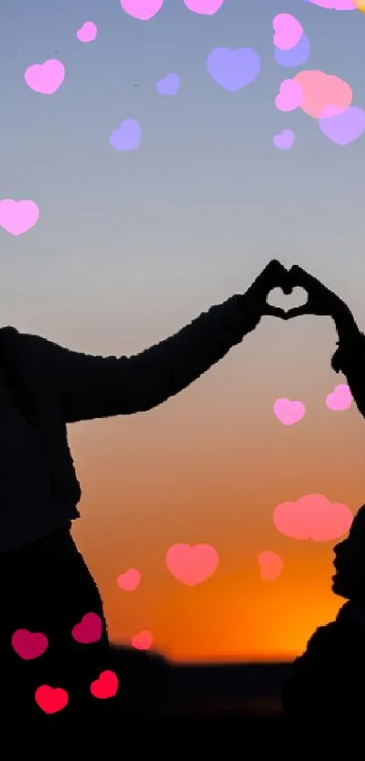 Silhouettes at sunset making a heart shape with vibrant orange and blue sky.