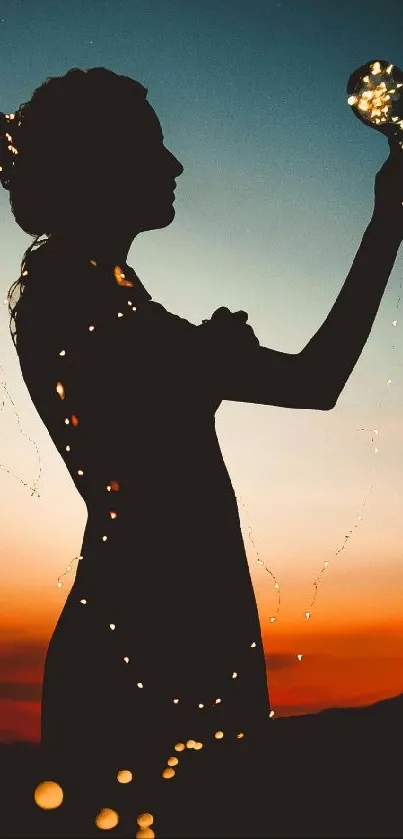 Silhouette of woman holding lights at sunset with orange hues.