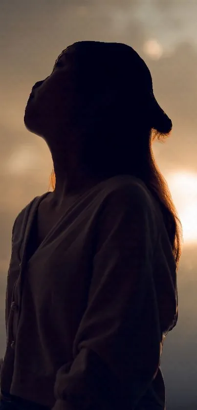 Silhouette of a woman against sunset sky.