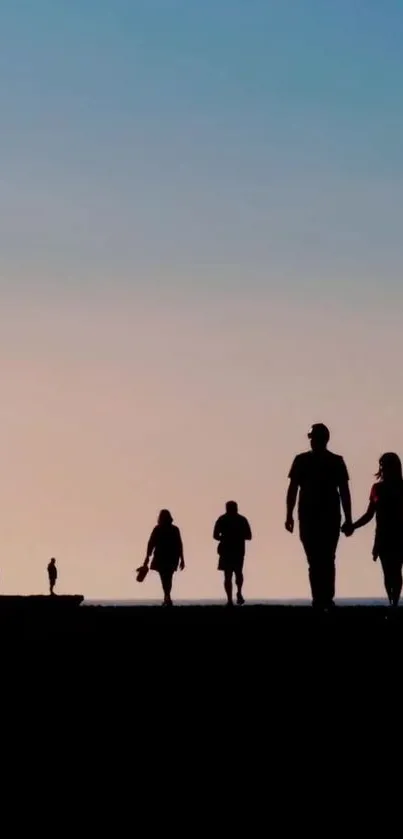 Silhouette sunset with people walking on a beach under a gradient sky.