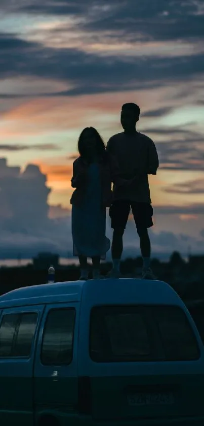 Couple silhouetted against sunset, standing on a van roof.