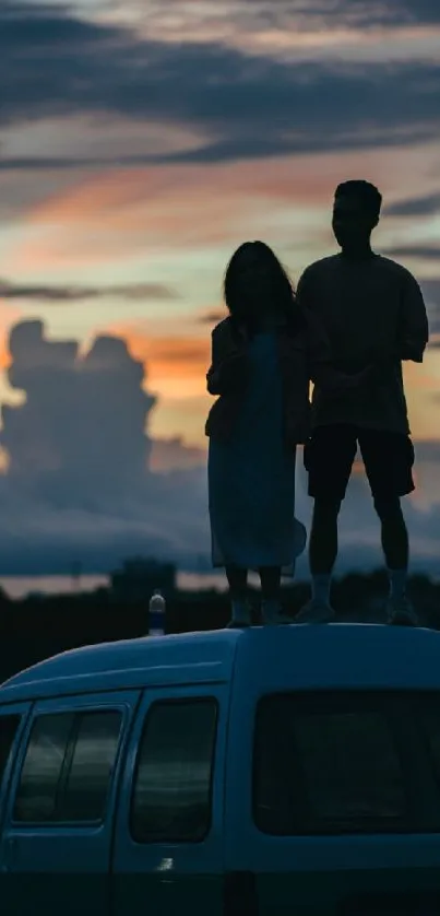 Silhouette of couple standing on a car roof against a sunset sky.