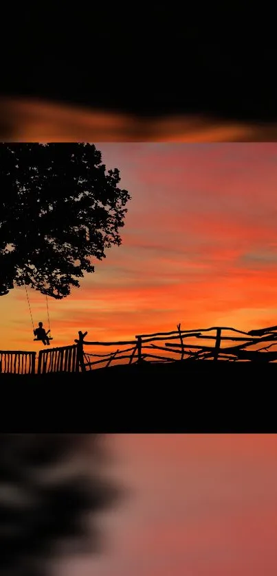 Silhouette of a tree and swing against an orange sunset.