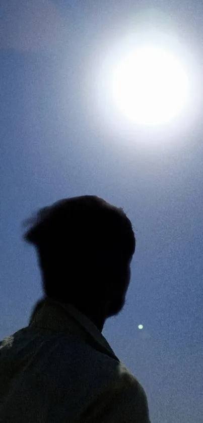 Silhouette of a person under a bright full moon in the night sky.