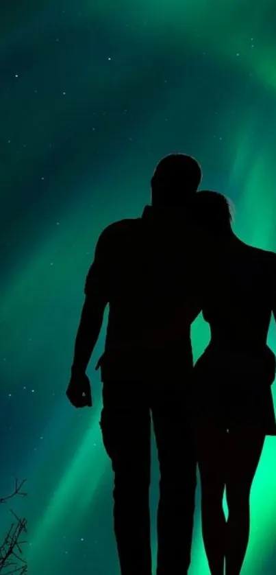 Silhouetted couple gazing at Northern Lights in a starry night sky.