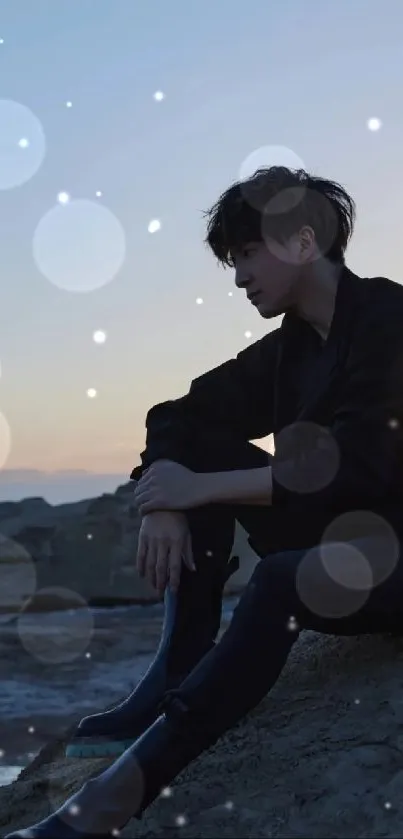 Silhouetted person sitting by beach at sunset with navy blue tones.