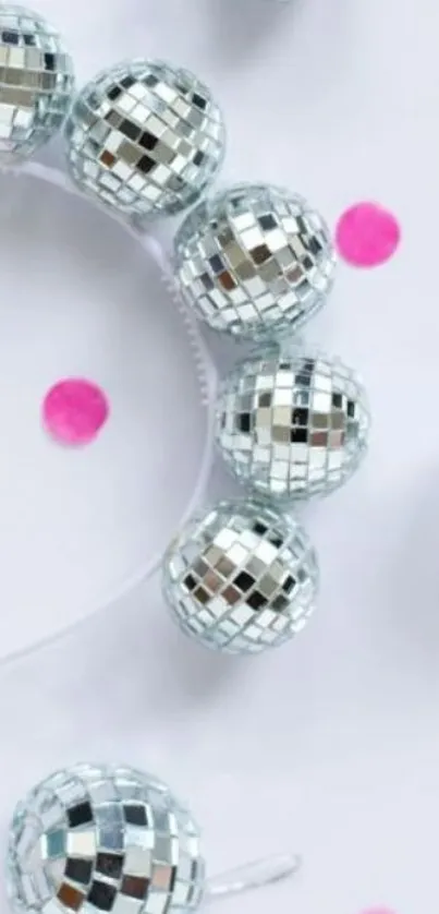 Glittering silver disco balls with pink dots on a white background.