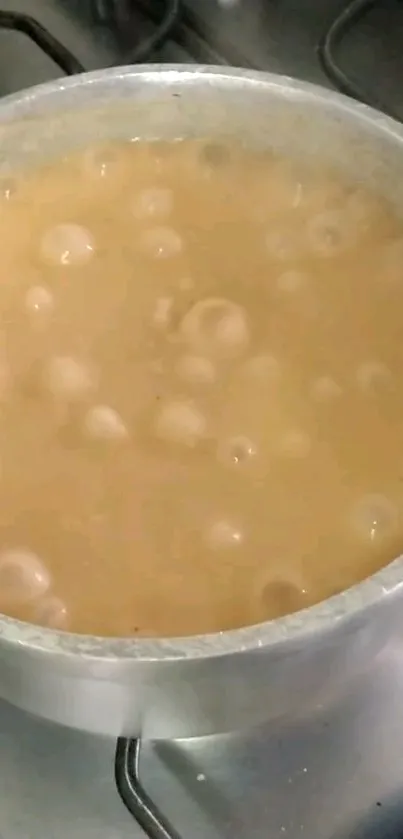 Milk boiling in a pot on a gas stove with bubbles.