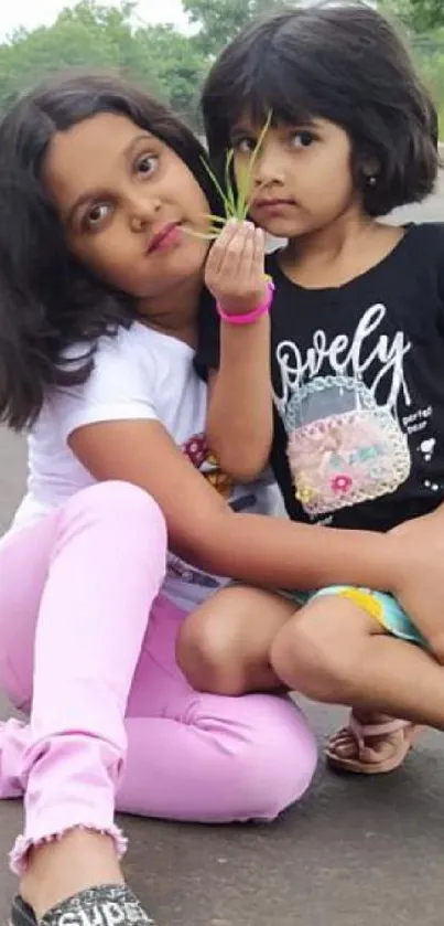 Two sisters seated by a road, bonding in nature.