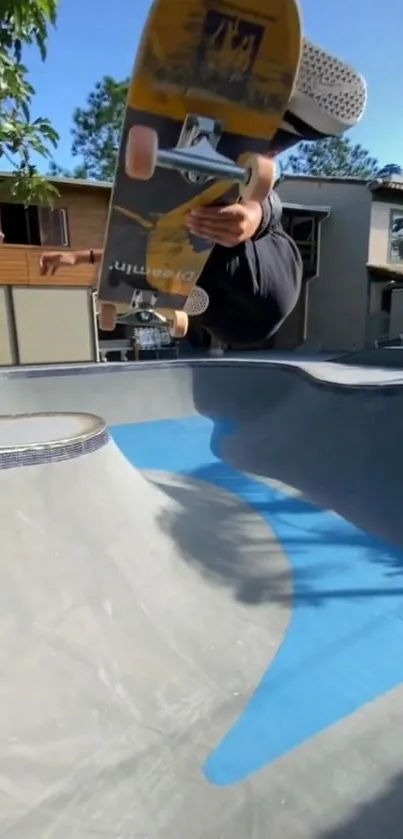 Skateboarder doing aerial trick in a sunlit skatepark with a clear blue sky.