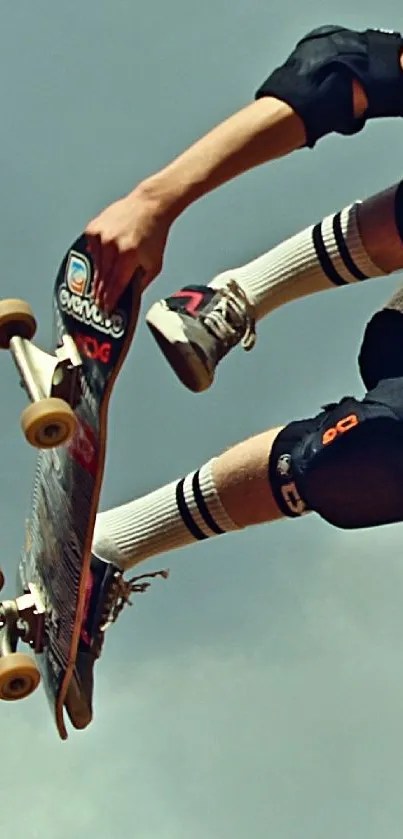 Skateboarder performing a mid-air trick against a grey sky.