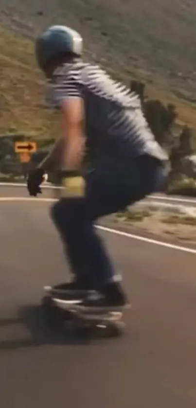 Skateboarder on winding mountain road, captured in motion.