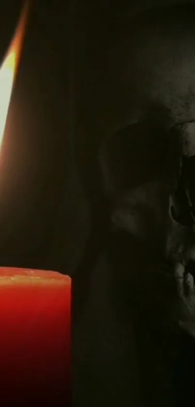 A red candle illuminating a skull in the dark.