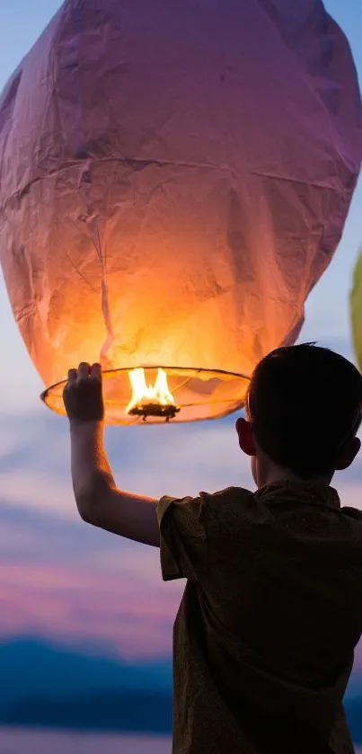 Child releasing a glowing lantern at sunset.